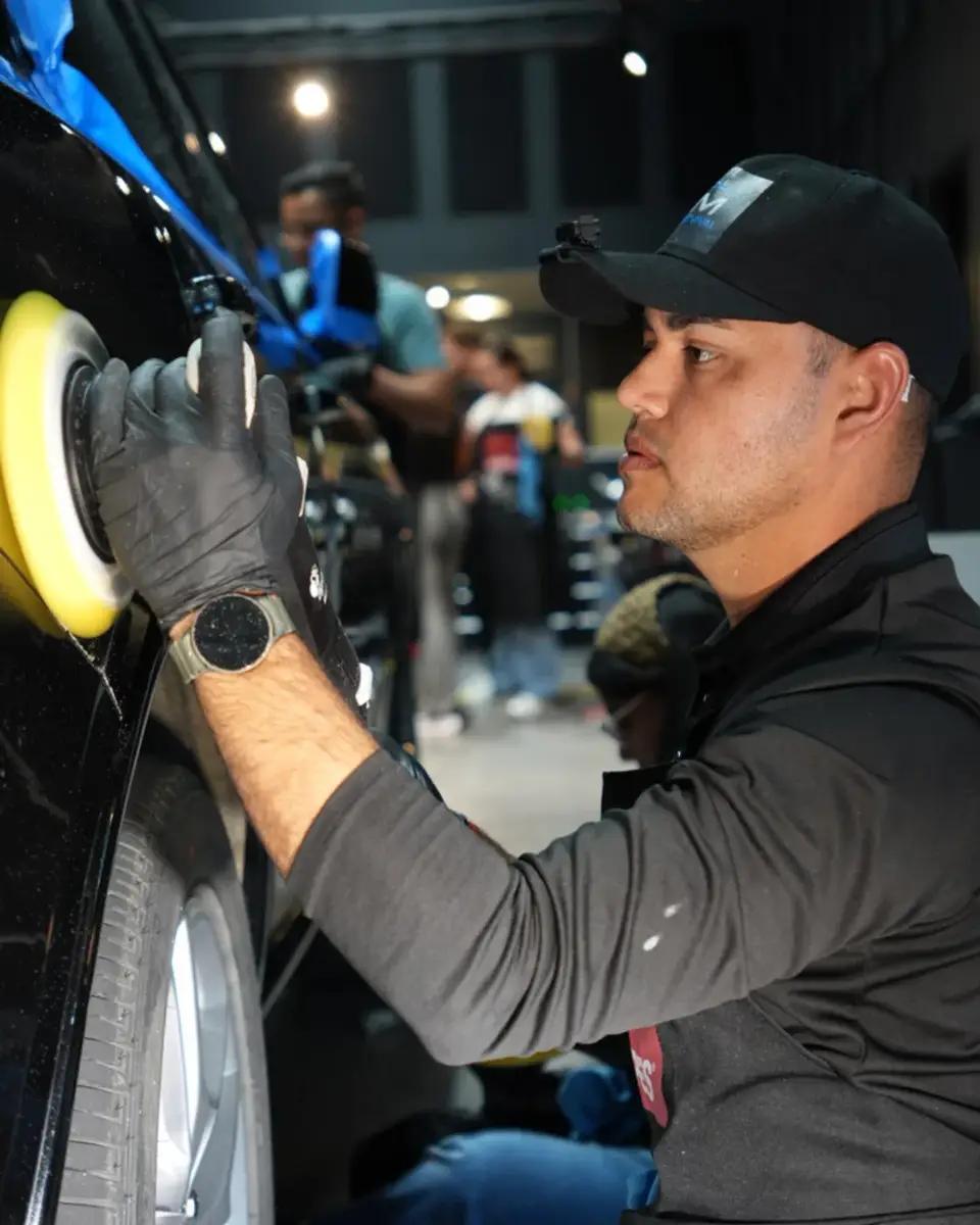 RM Auto Revival technician machine-polishing a black car during paint correction in Miami